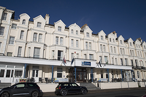 Exterior of Best Western York House Hotel. A large white hotel with bay windows with blue skies behind.